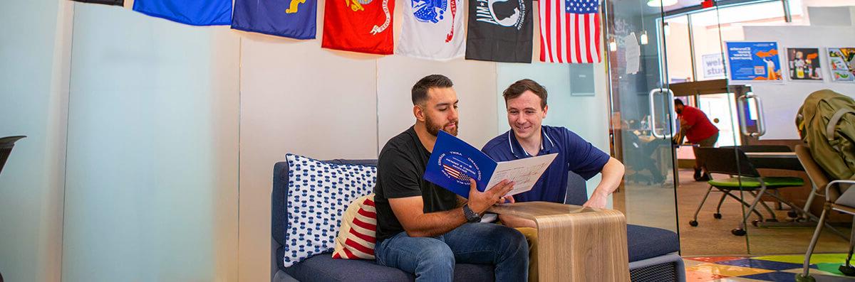 A veteran student works in a veteran services center with the help of a Staff member